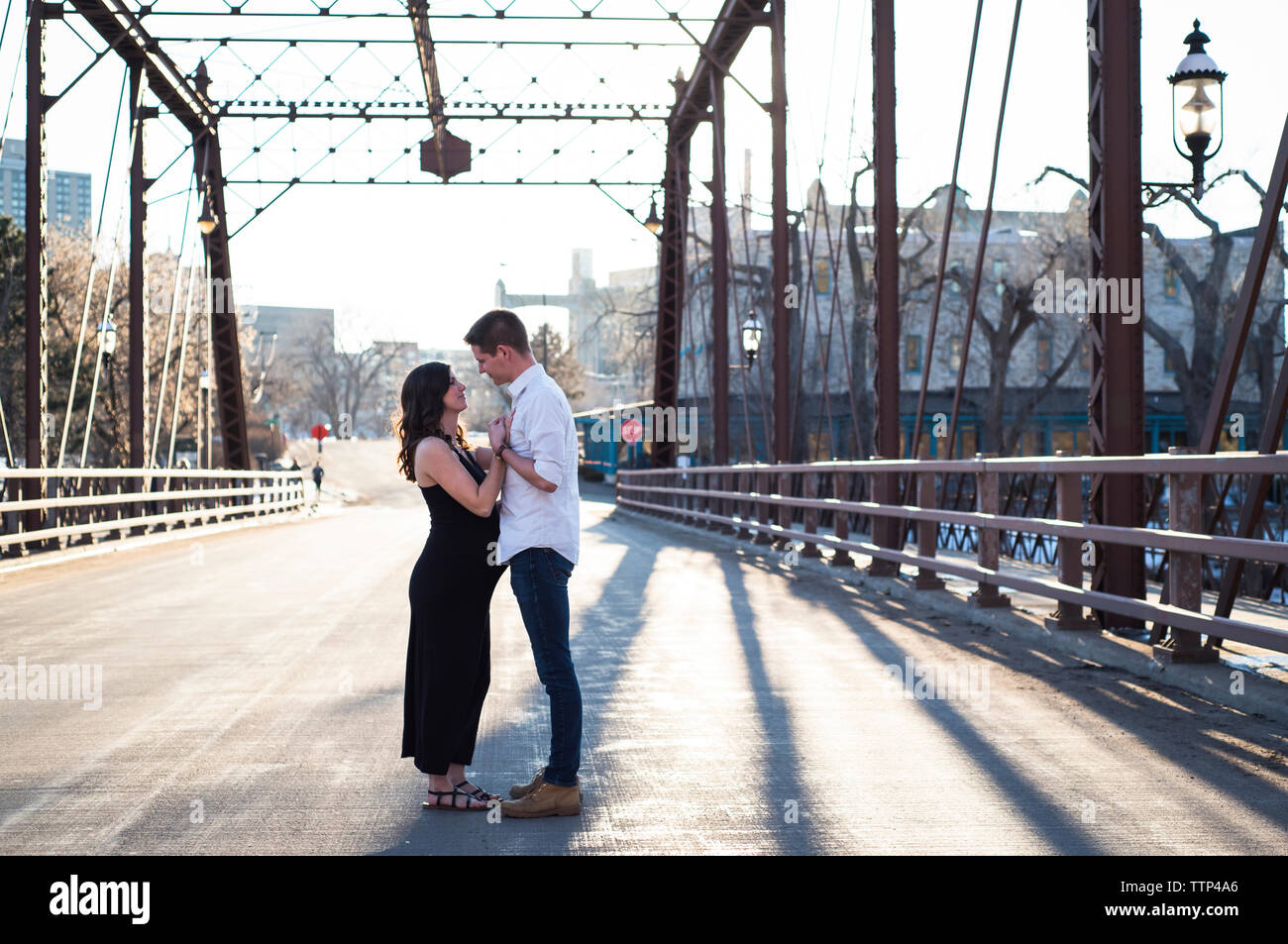 Seitenansicht des Romantisches Paar sich einander beim Stehen auf der Brücke gegen den klaren Himmel Stockfoto