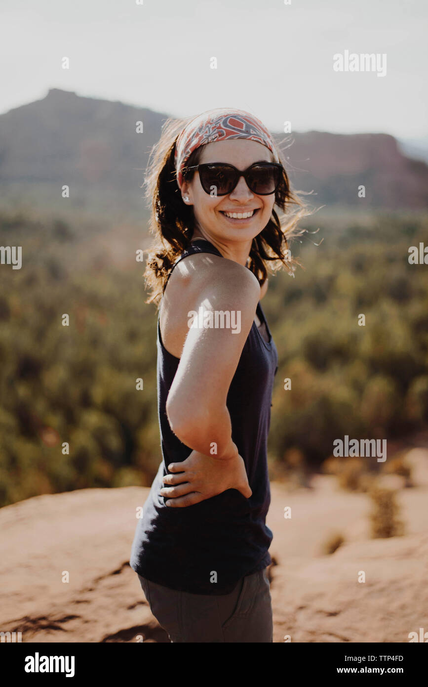 Lächelnde junge Frau auf Rock gegen Berge Stockfoto