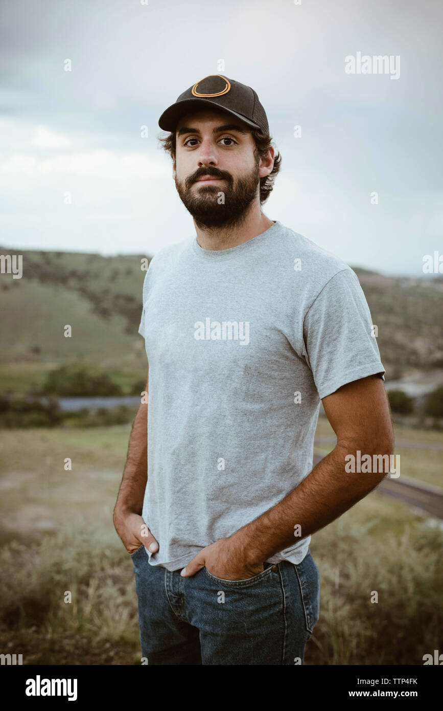 Portrait von zuversichtlich Mann stand mit den Händen in den Taschen in das Feld Stockfoto