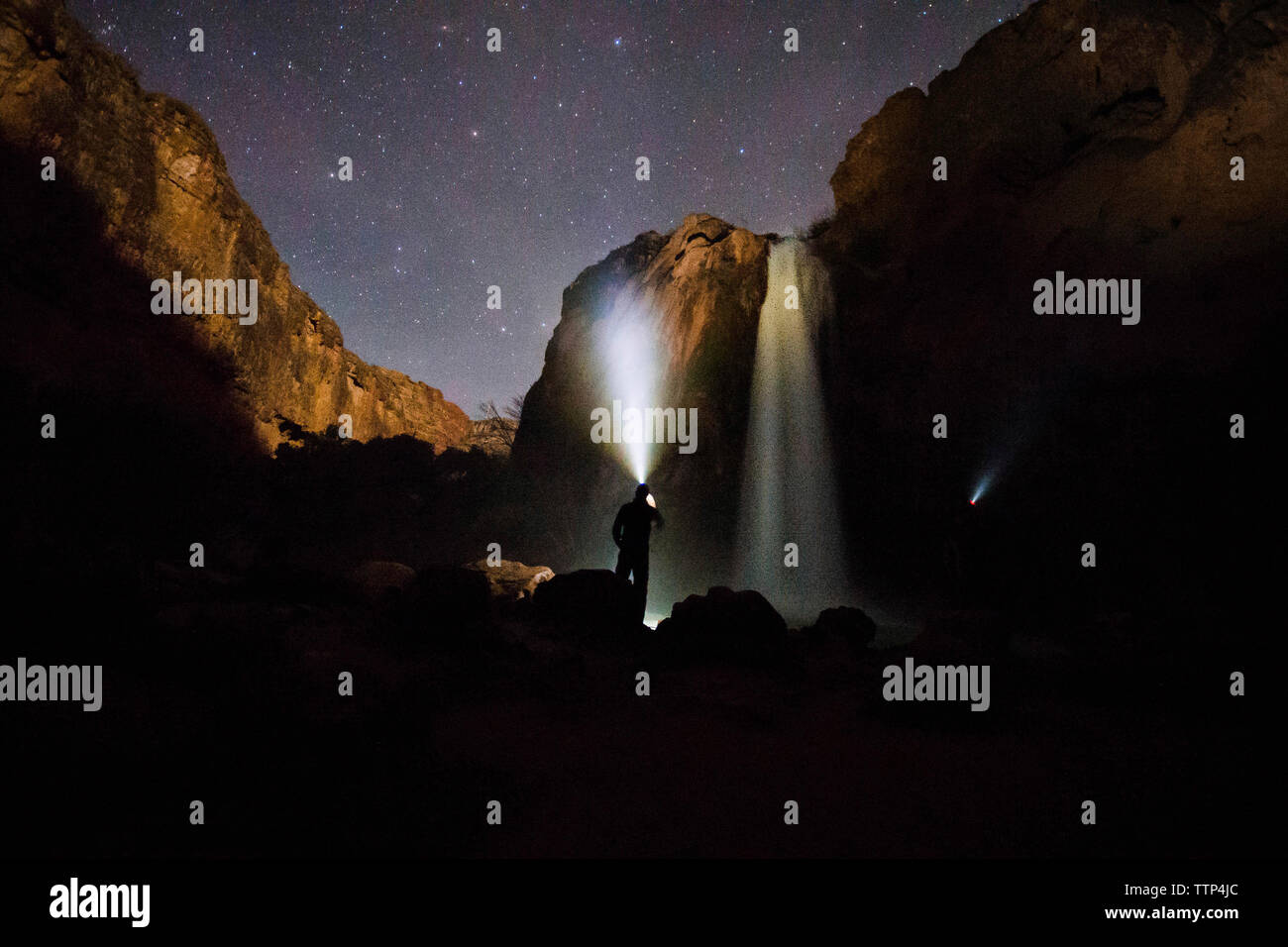 Silhouette Mann mit Taschenlampe stehen Wasserfall bei Nacht Stockfoto
