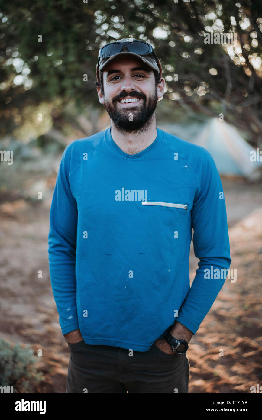 Portrait von lächelnden Mann mit Händen in den Taschen am Wald Stockfoto