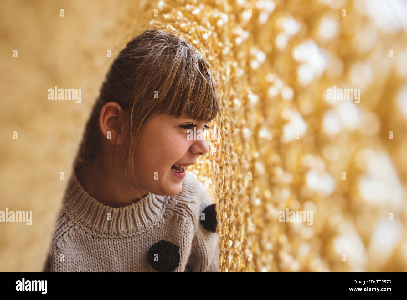 Mädchen lachend unter einer gelben Decke Stockfoto