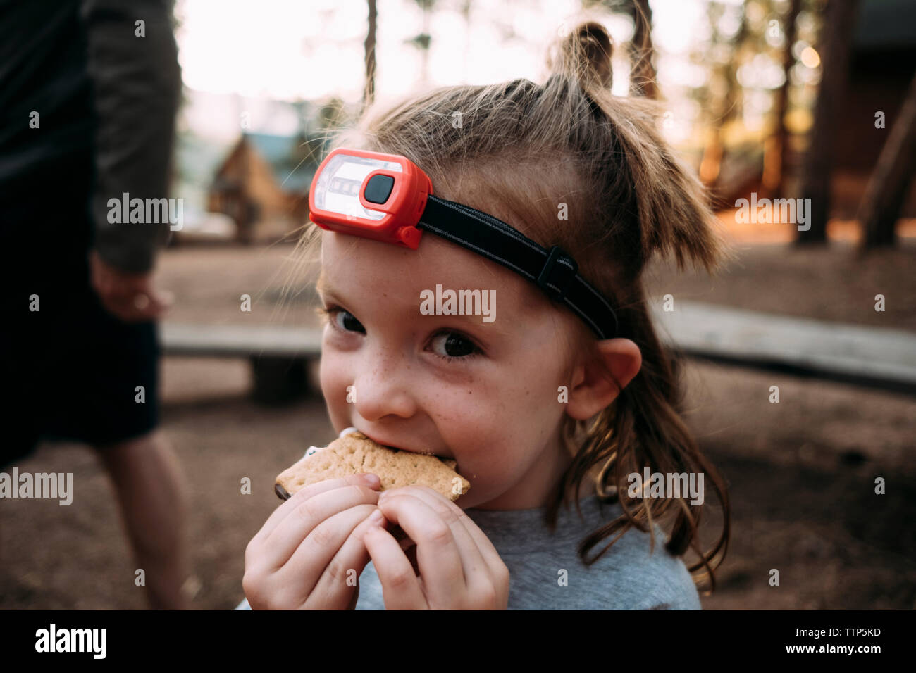 - Porträt der niedliche Mädchen Süßigkeiten essen Nahe beim Stehen in Wald Stockfoto