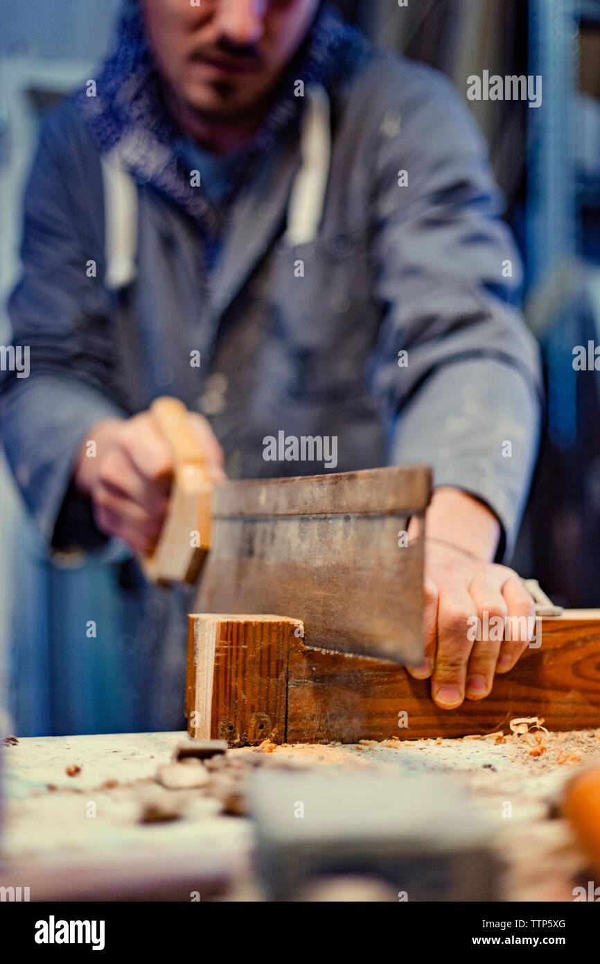 Mittelteil der männlichen Tischler Sägen von Holz in der Werkstatt Stockfoto