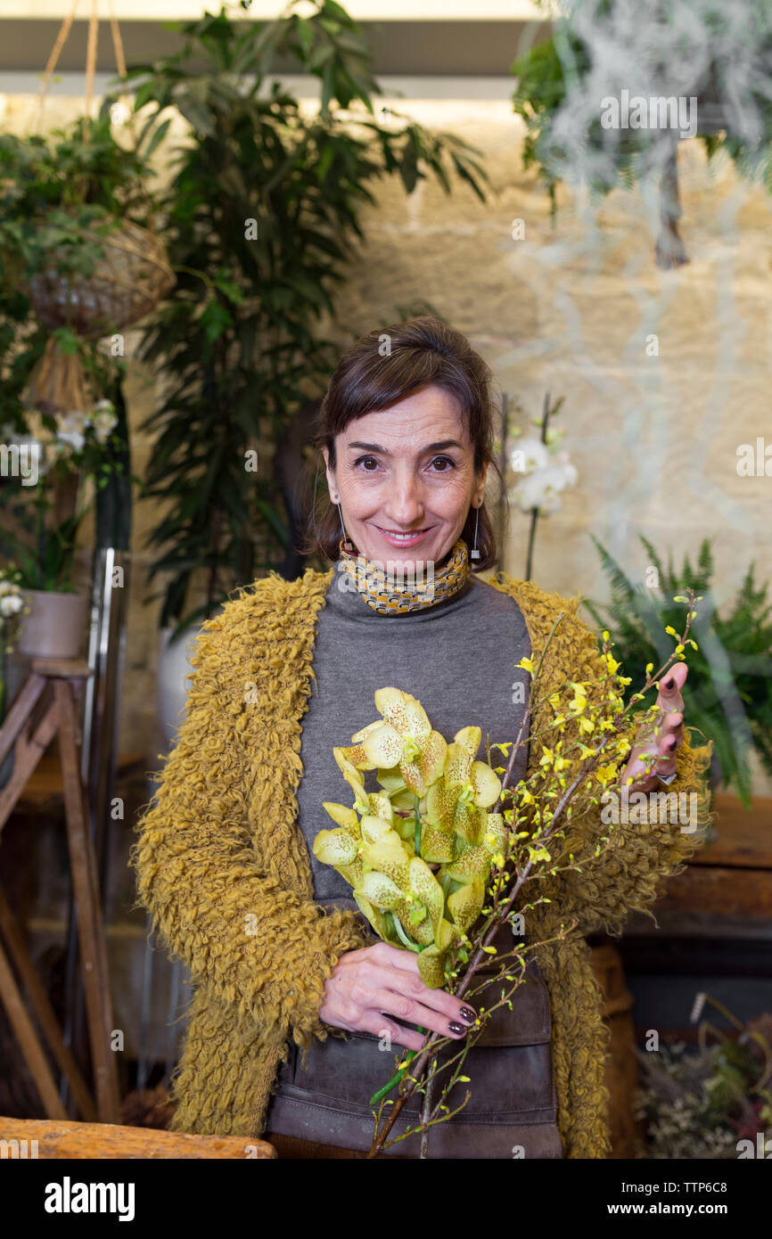 Portrait von fröhlichen älteren Frau mit gelben Blumen Blumengeschäft Stockfoto