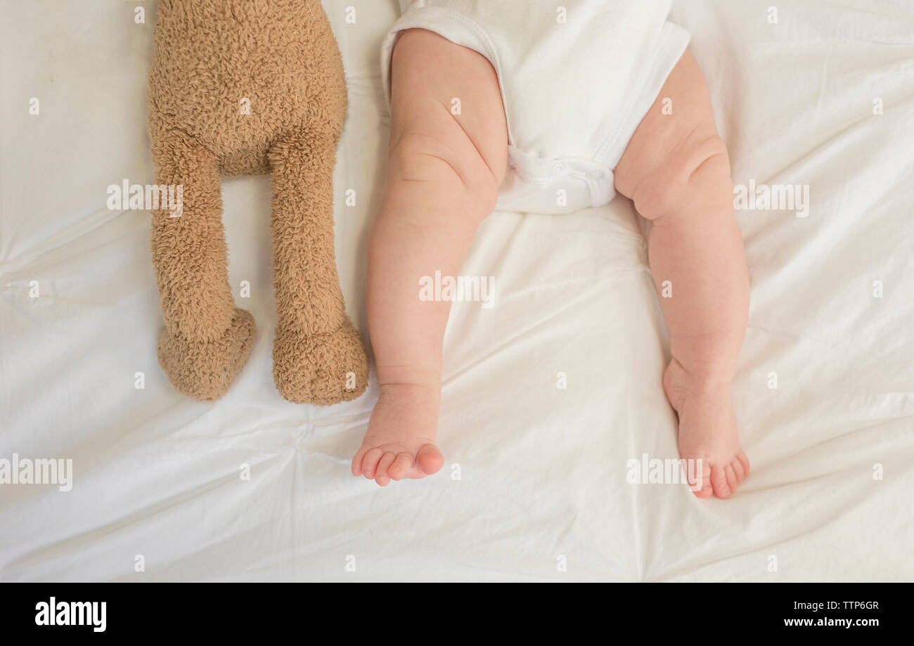 Niedrige Abschnitt von Baby Mädchen mit stofftier auf Bett zu Hause liegen Stockfoto