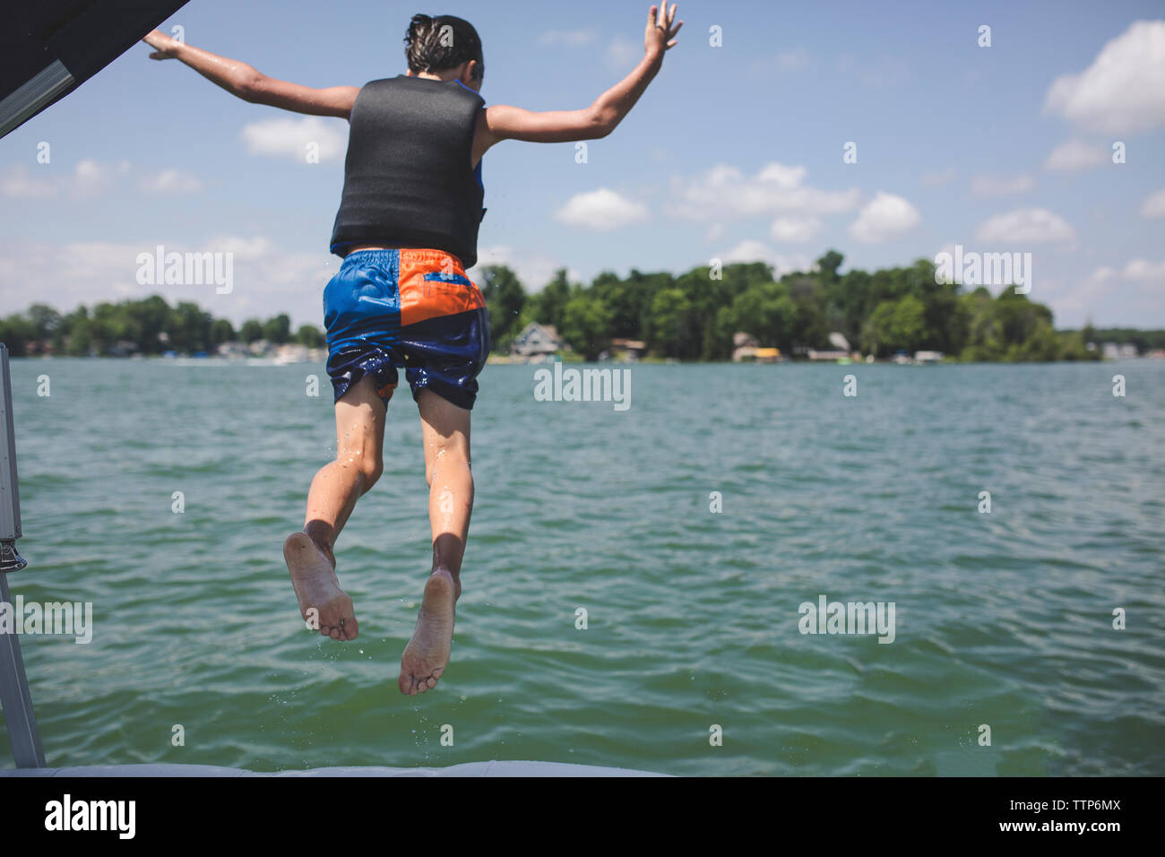 Ansicht der Rückseite des Jungen springen in Fluss gegen Sky Stockfoto
