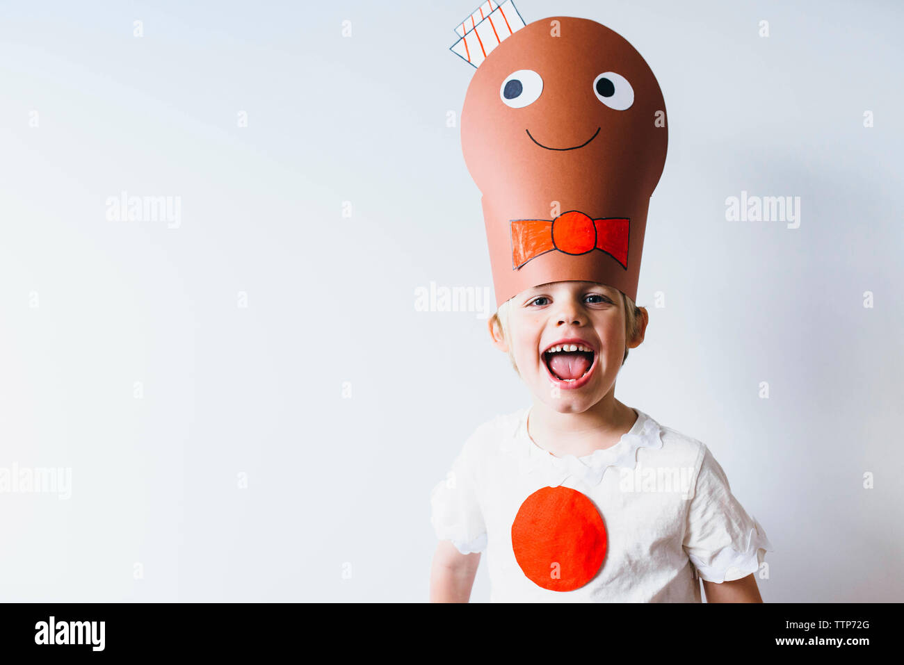 Porträt des jungen tragen Papier headwear Während gegen die Wand Stockfoto