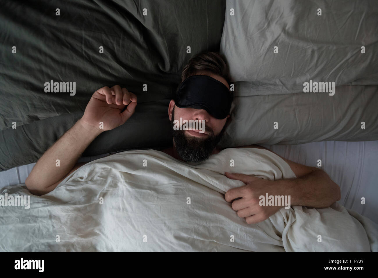 Hohe Betrachtungswinkel von Mann, Schlafmaske, während am Bett zu Hause schlafen Stockfoto