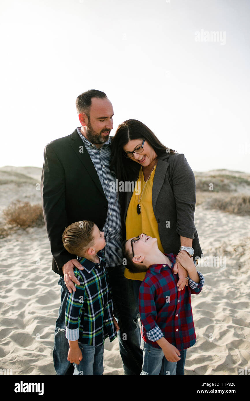 Glückliche Eltern mit Kinder am Strand gegen klaren Himmel während der sonnigen Tag Stockfoto