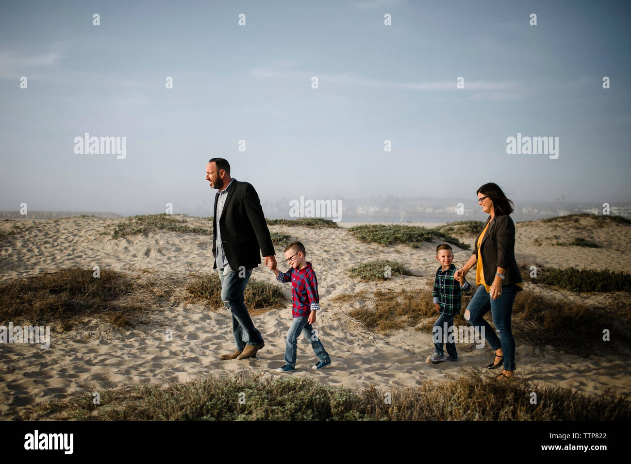 Seitenansicht der Eltern mit den Kindern zu Fuß am Strand gegen Himmel während der sonnigen Tag Stockfoto