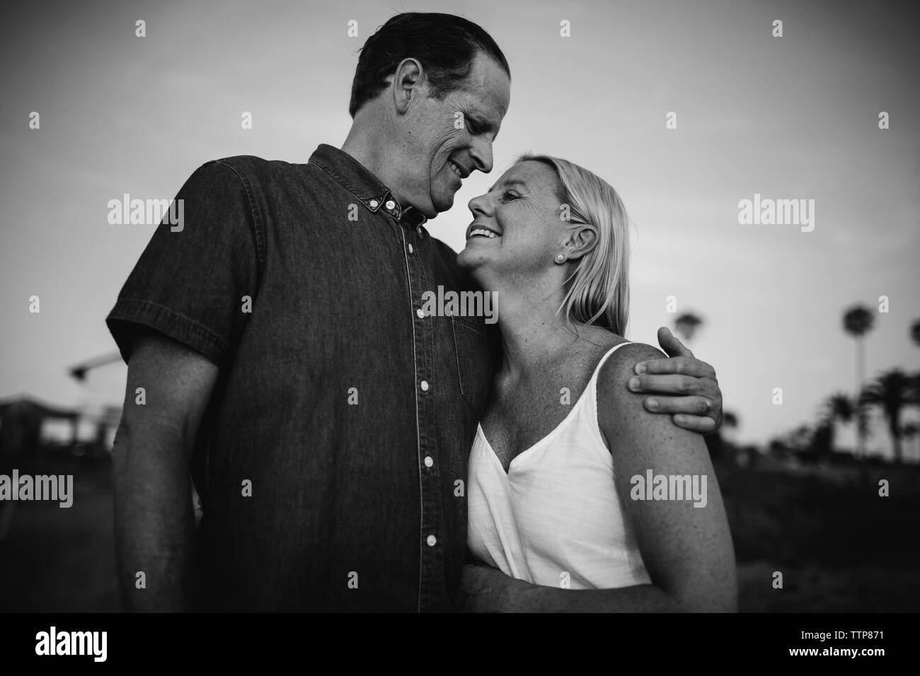 Low Angle View von romantisches Paar sich einander beim Stehen auf Klippe gegen Himmel bei Sonnenuntergang Stockfoto