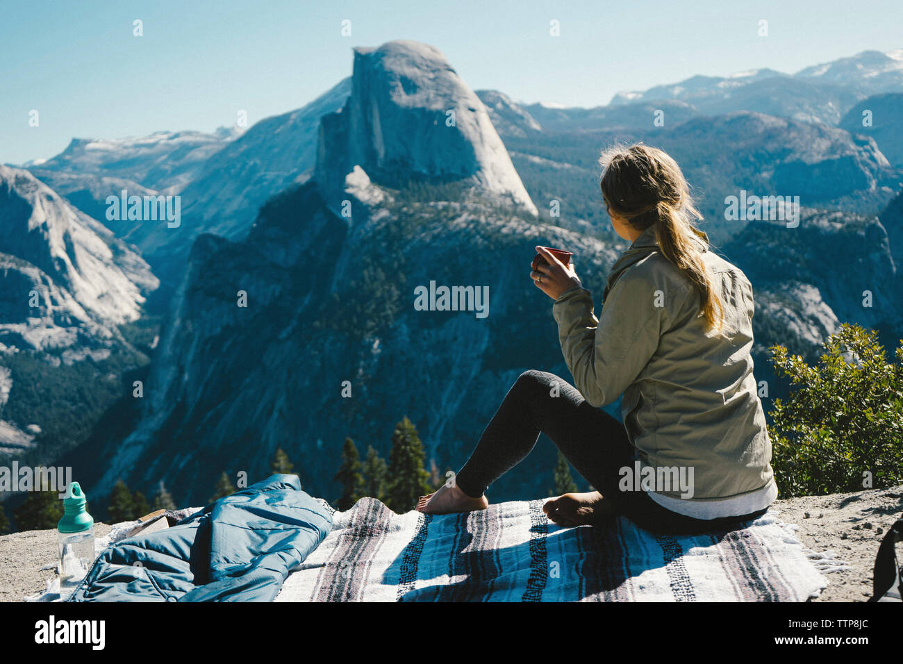 Volle Länge des weiblichen Wanderer in Getränk, während Sie auf dem Berg im Yosemite National Park sitzen während der sonnigen Tag Stockfoto