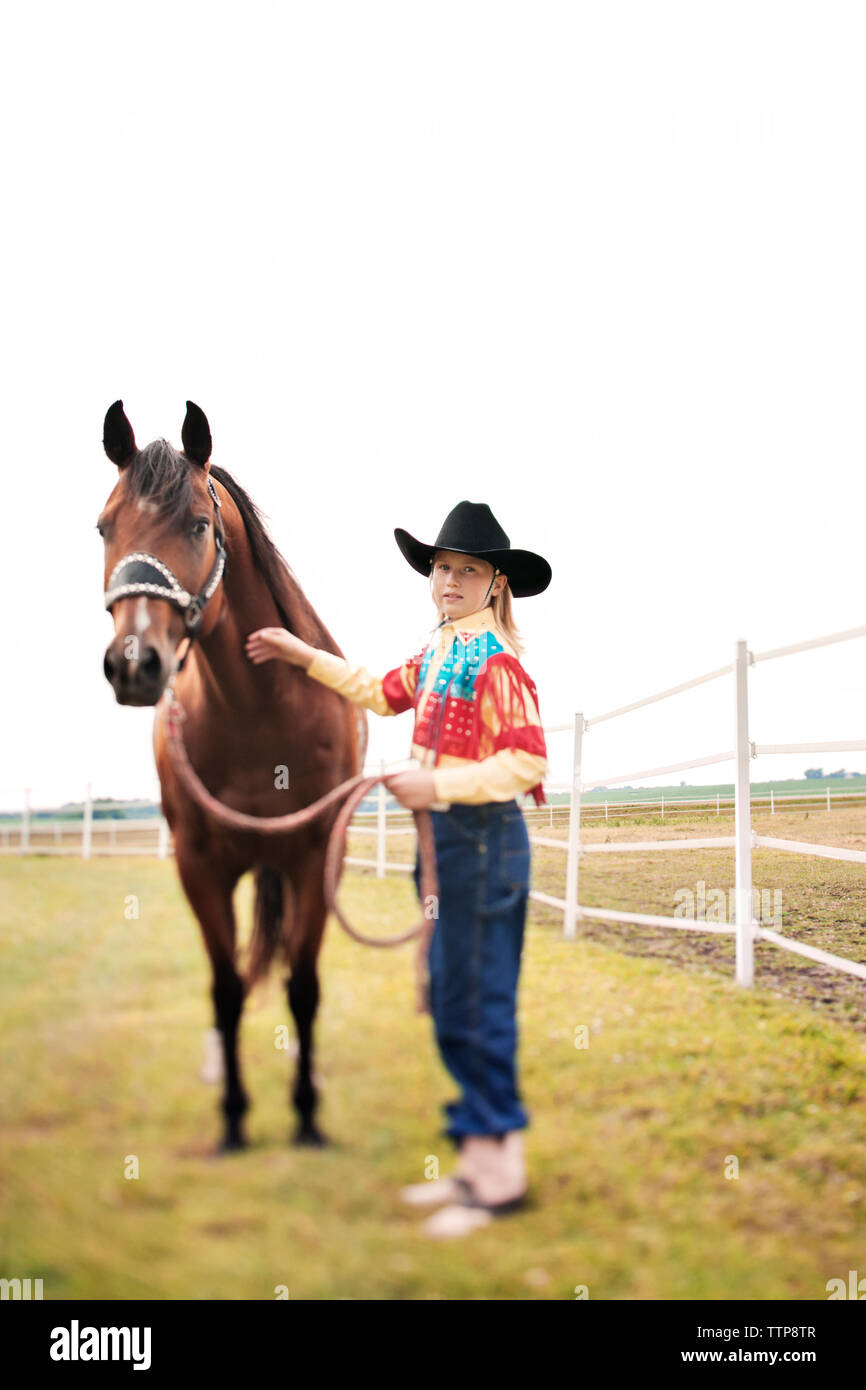 Portrait von lächelnden stehendes Mädchen mit Pferd im Stift gegen klaren Himmel Stockfoto