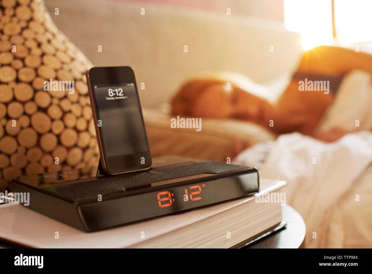 Smart Phone auf modernen Wecker im Schlafzimmer Stockfoto