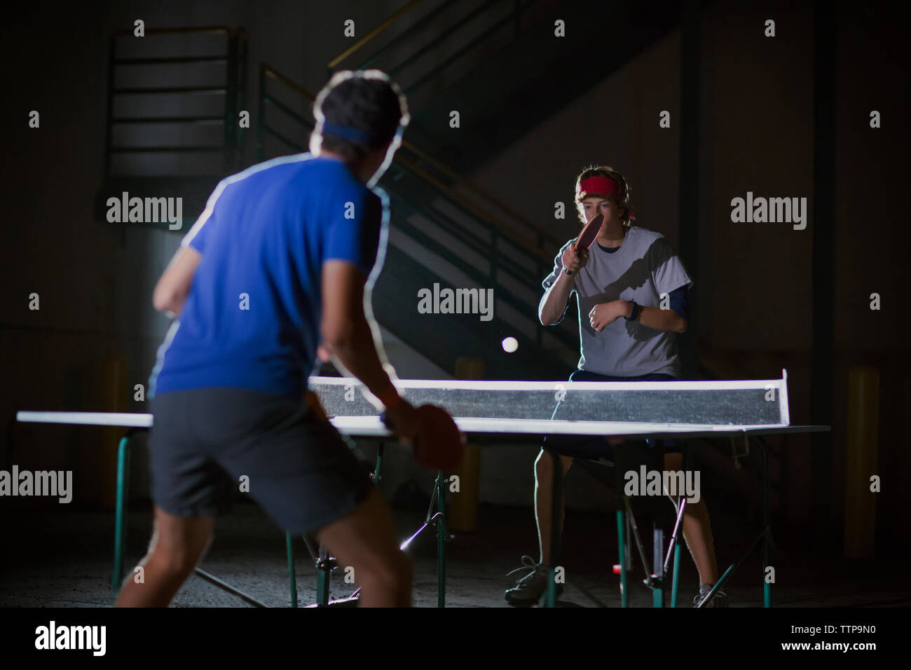 Männer spielen Tischtennis gegen beleuchtete Gebäude Stockfoto