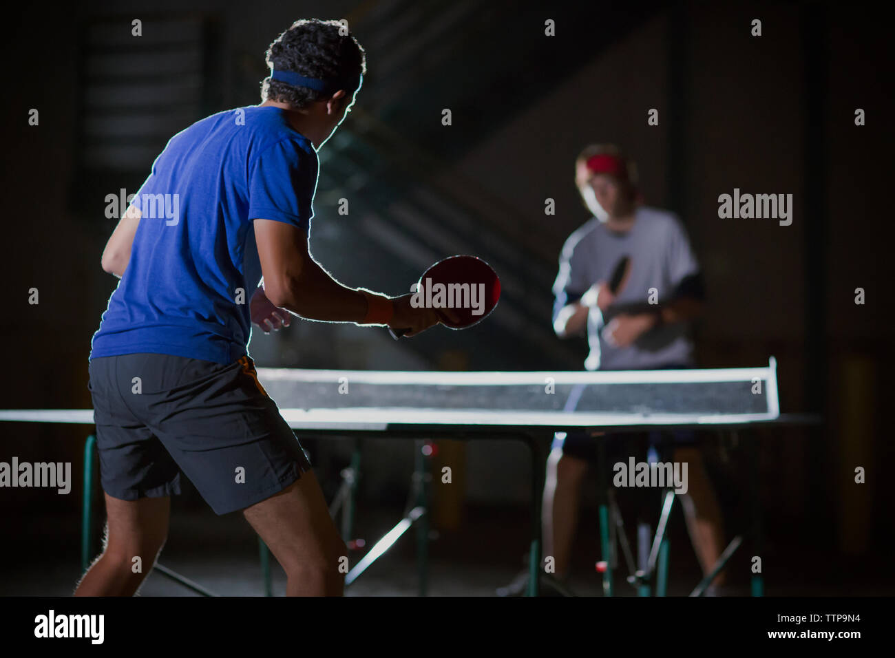 Freunde Tischtennis spielen gegen beleuchtete Gebäude Stockfoto