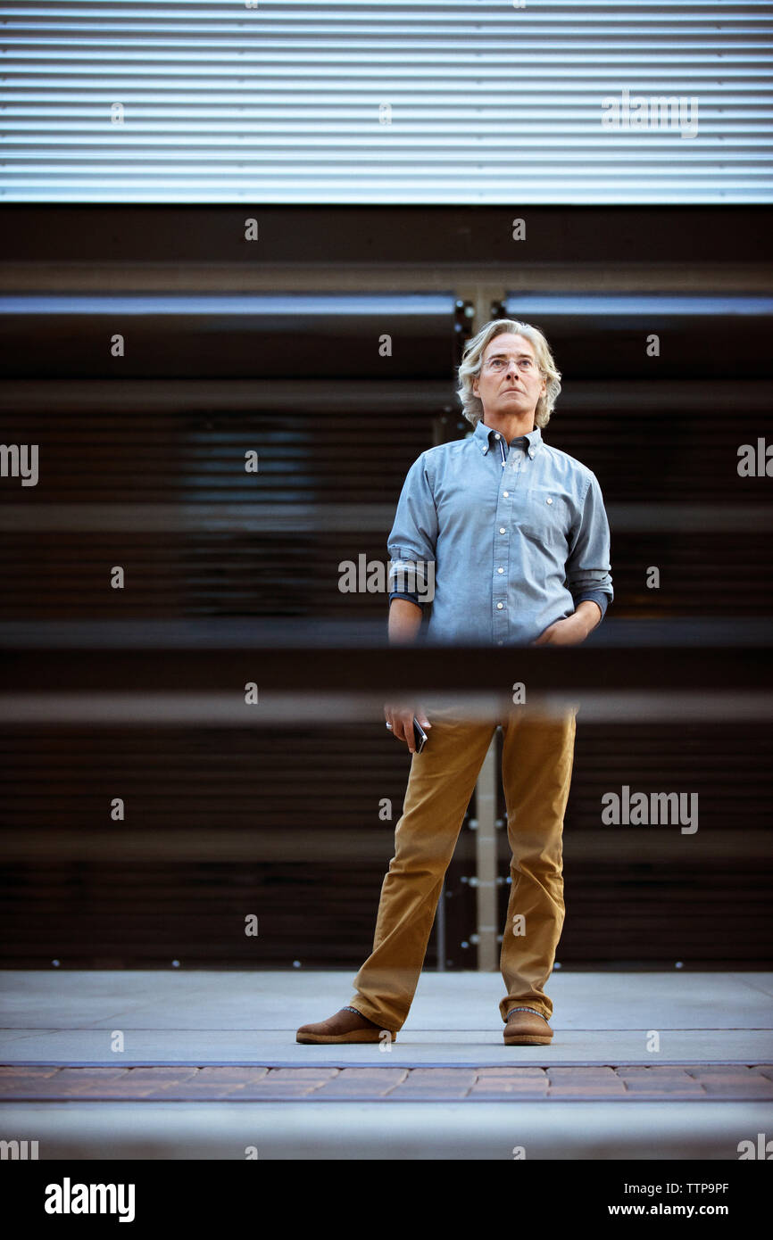 Reifer Mann stehend auf dem Boden mit der Hand in der Tasche Stockfoto