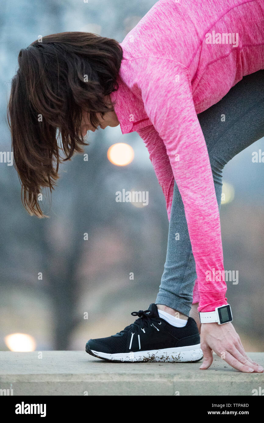 Seitenansicht der Frau Ausübung auf Stützmauer in Park Stockfoto