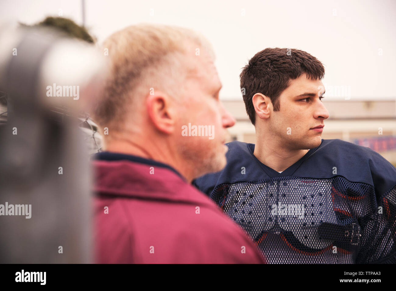 Trainer und American football player Weg schauen, während bei Stadion stehend Stockfoto