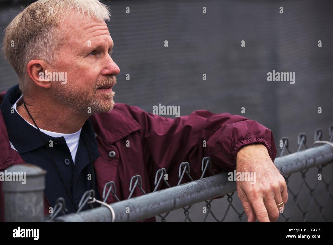 American Football Trainer weg schauen, während Sie durch Zaun am Stadion stehend Stockfoto