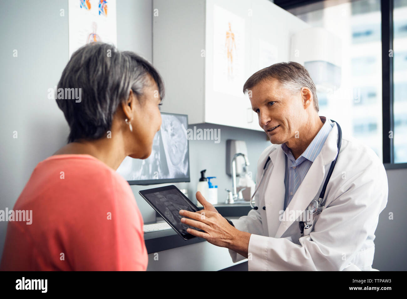 Männlicher Arzt erklären, x-ray auf Tablet Computer zu Patienten in der Klinik Stockfoto