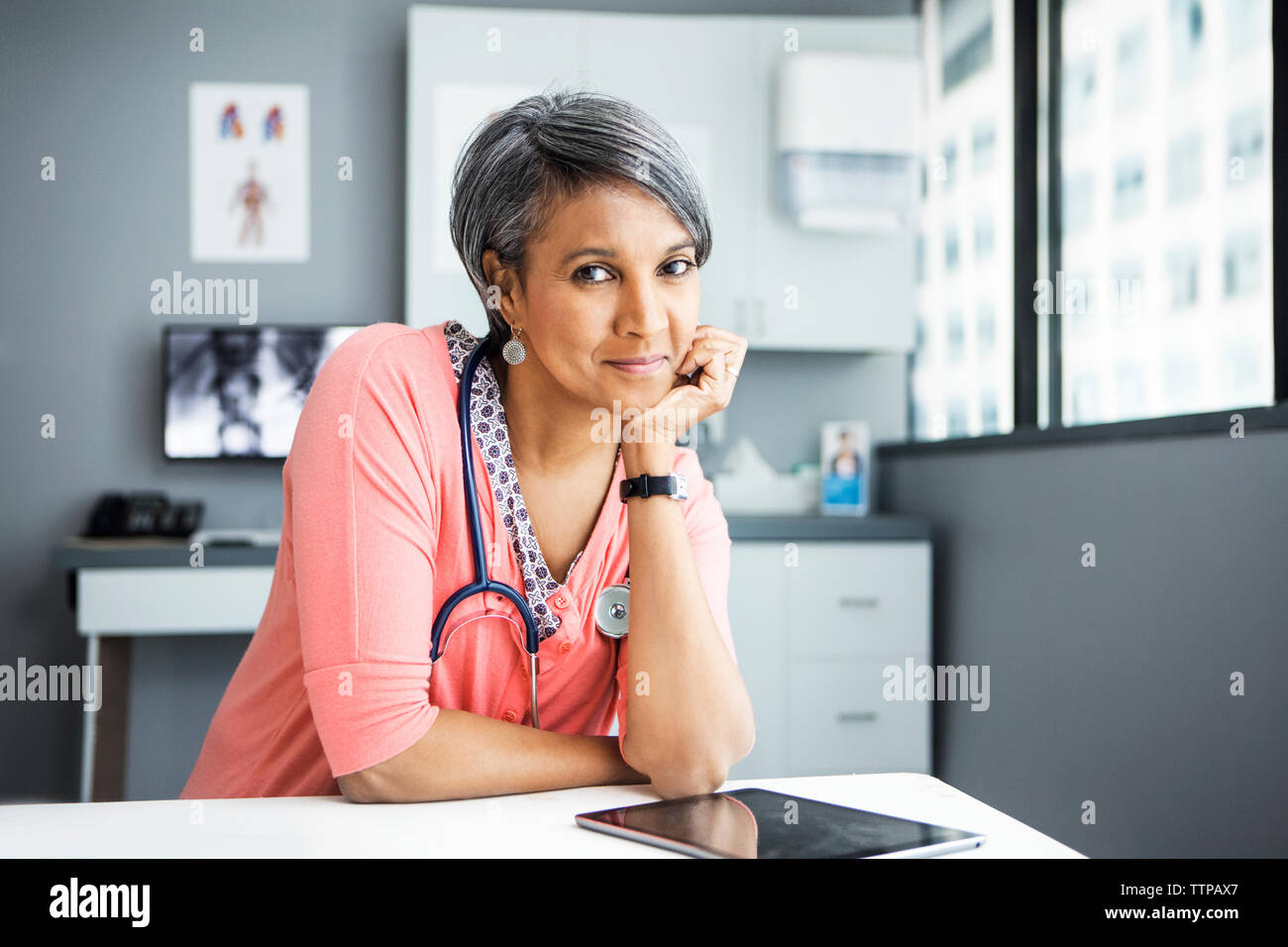 Portrait von zuversichtlich Ärztin lehnte sich auf dem Schreibtisch, in der Klinik Stockfoto