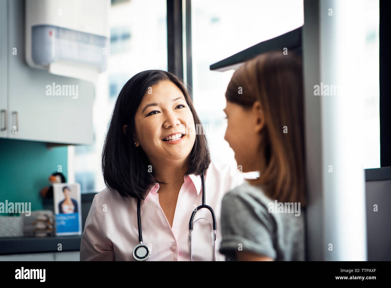 Lächelnd Höhe der Frauen Arzt messen Mädchen in der Klinik Stockfoto