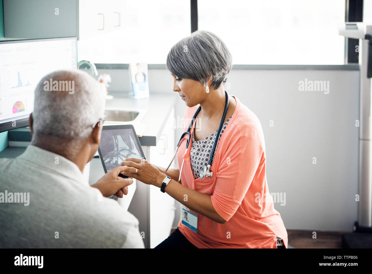 Ärztin erklären, x-ray zu Patienten auf Tablet-PC in der Klinik Stockfoto
