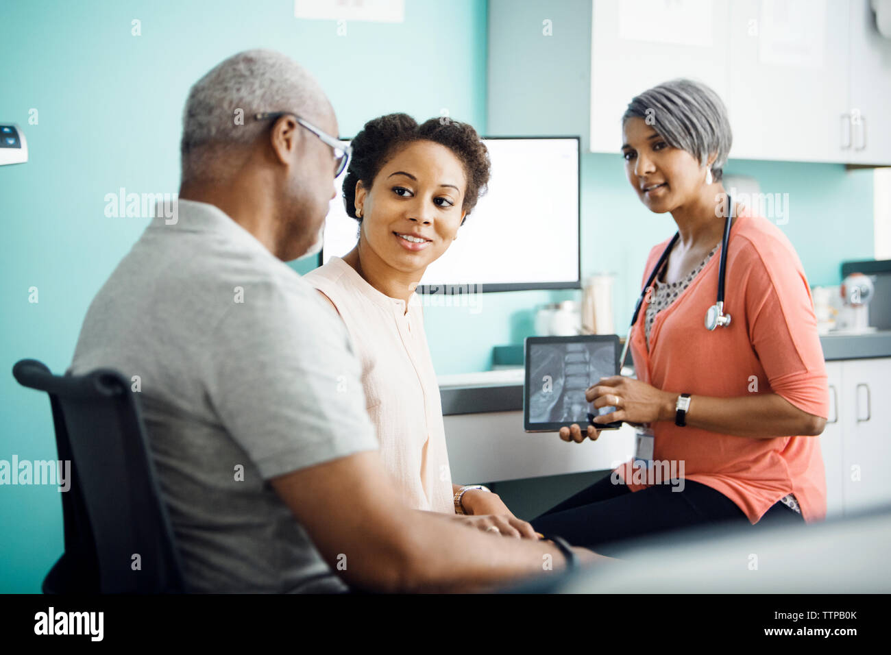 Tochter im Gespräch mit Vater während der Sitzung mit der Ärztin in der Klinik Stockfoto