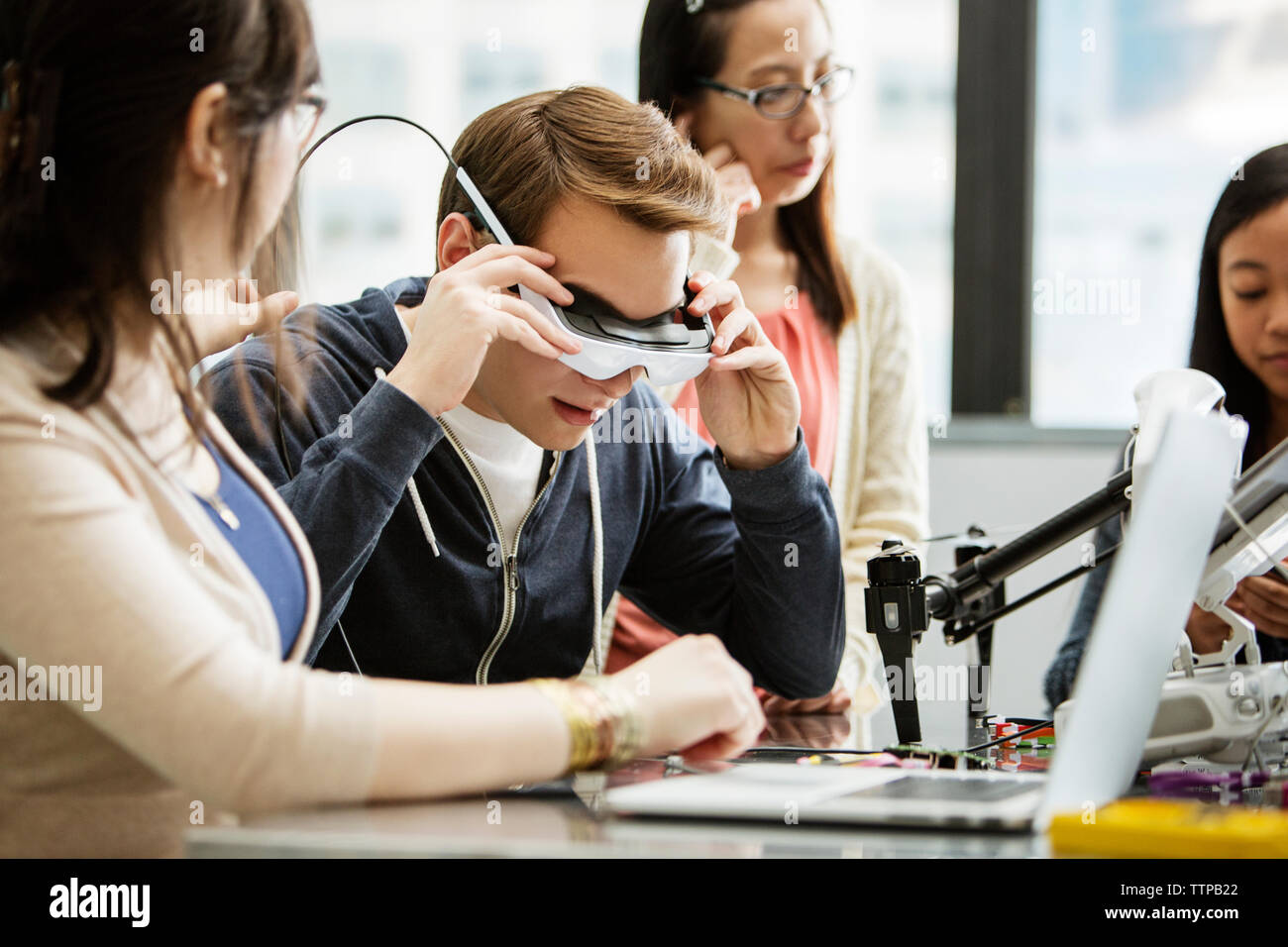 Männliche Student trägt die virtual reality Brillen, während sie von Freunden im Klassenzimmer sitzen Stockfoto