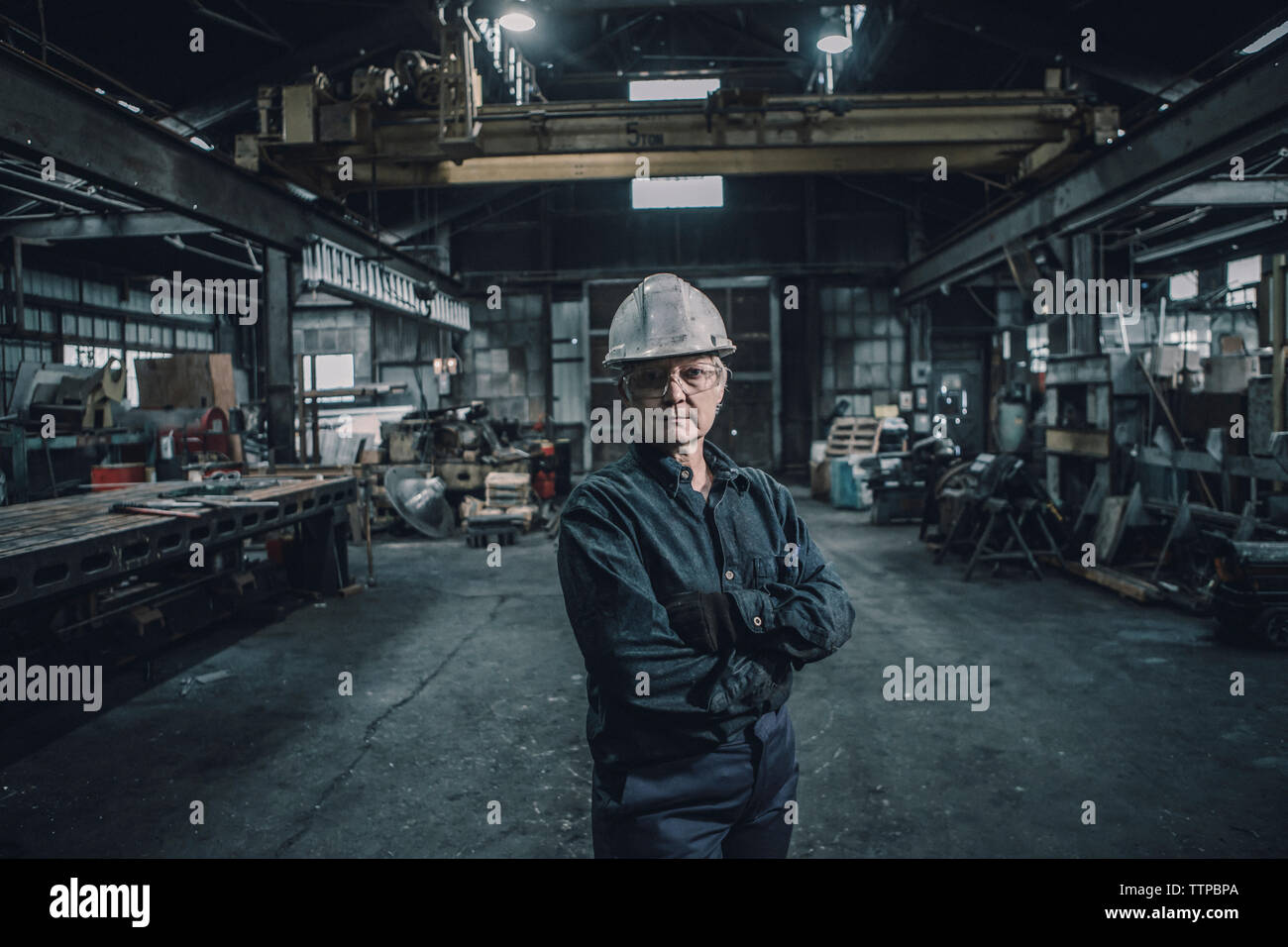 Portrait von zuversichtlich Arbeiterin mit gekreuzten Armen stehen in der Factory Stockfoto