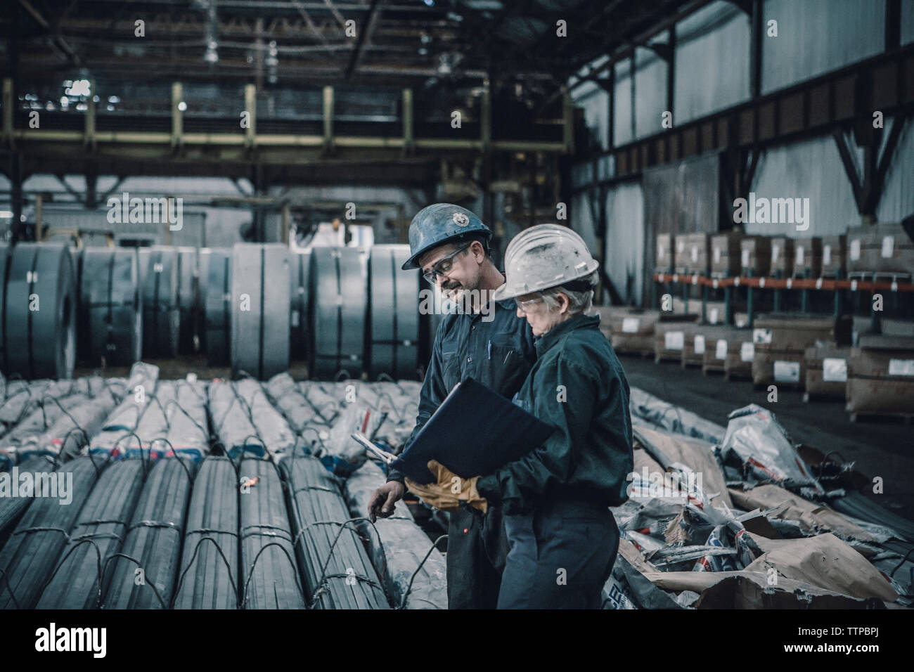 Mitarbeiter diskutieren Dokumente beim Gehen in der Metallindustrie Stockfoto