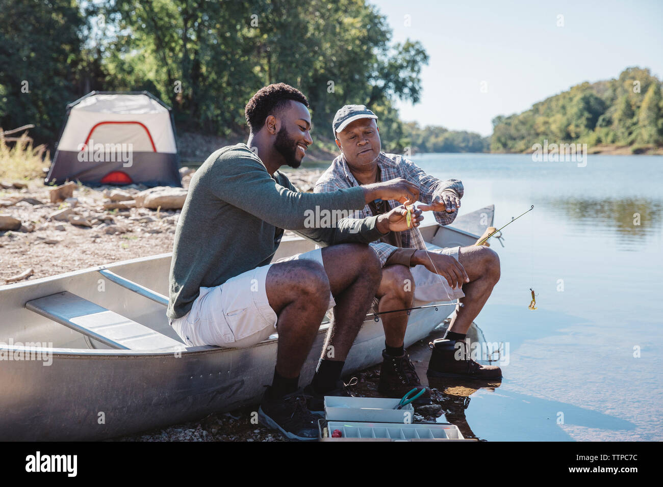 Freunde angeln Einstellen der Geräte auf dem Boot am Seeufer Stockfoto