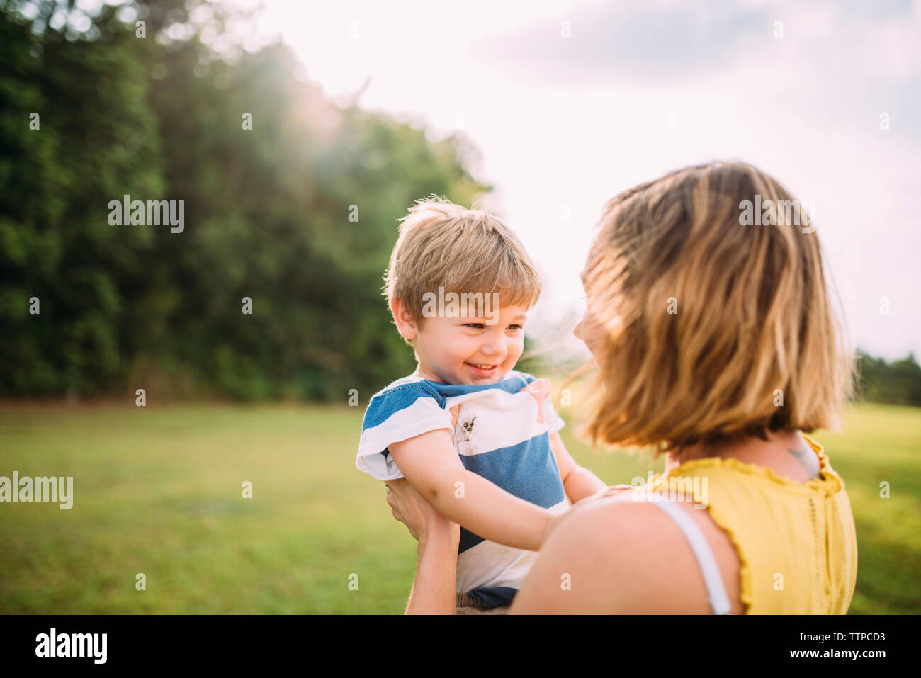 Glückliche Mutter anheben Sohn im Park Stockfoto