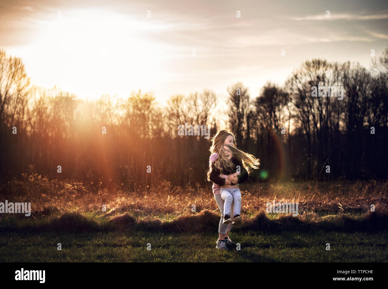 Zwei junge Mädchen twirling und Lachen in der Sonne Stockfoto