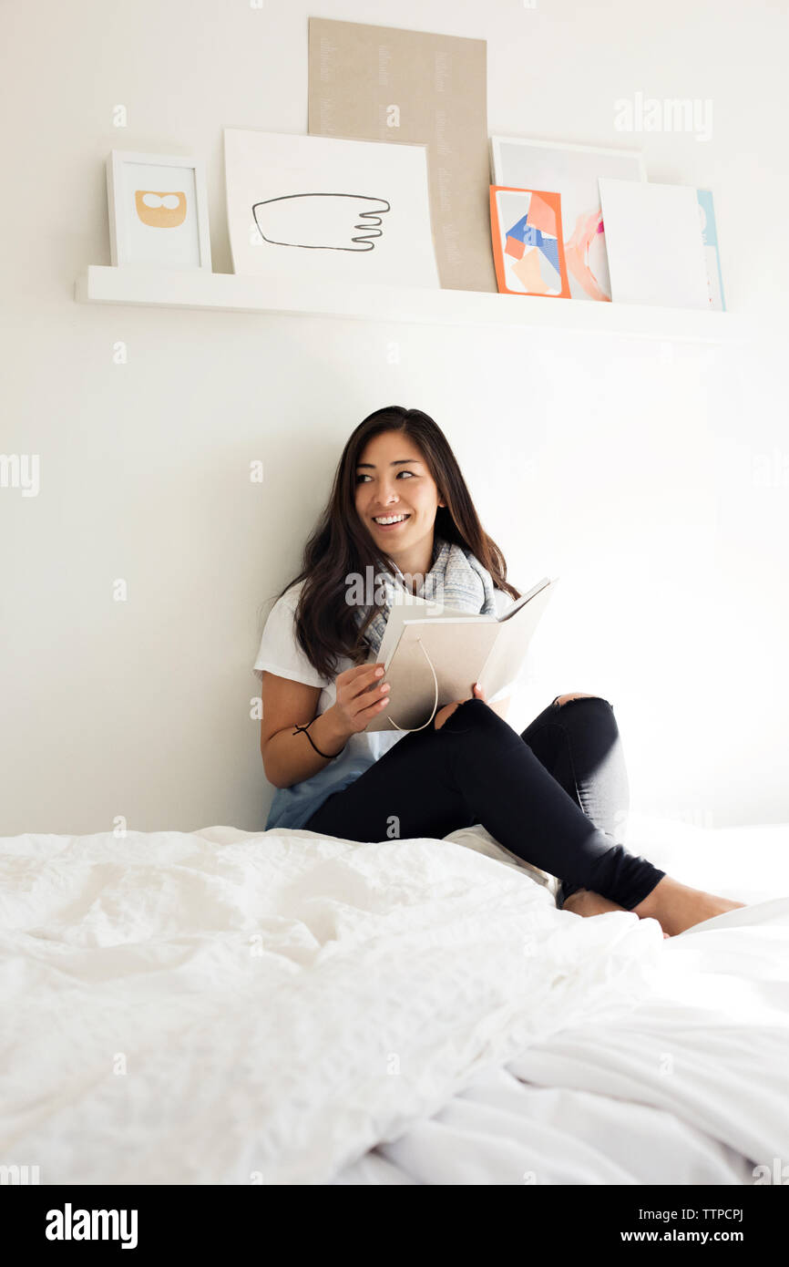Happy woman holding Tagebuch während auf dem Bett zu Hause sitzen Stockfoto