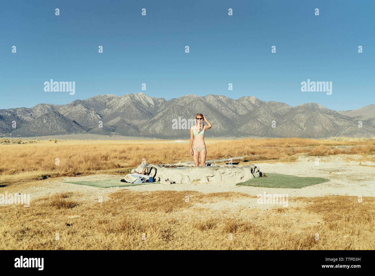 Frau im Pool auf dem Feld von Bergen gegen den klaren Himmel Stockfoto