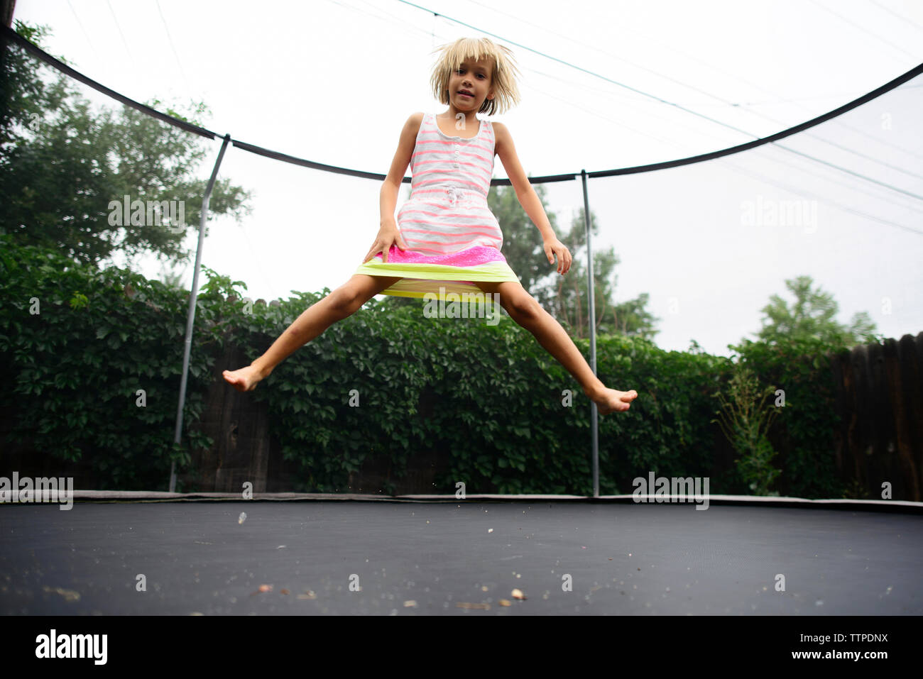Low Angle Portrait von Mädchen springen auf Trampolin im Park gegen den klaren Himmel Stockfoto