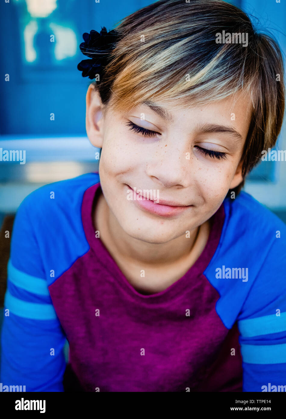 Nahaufnahme der lächelnde Mädchen mit geschlossenen Augen zu Hause sitzen Stockfoto