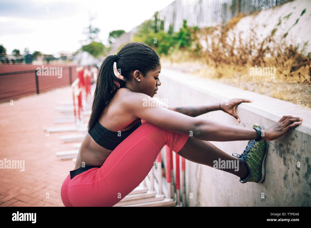 Seitenansicht des weiblichen Athleten stretching Bein auf der Stützmauer bei Stadion Stockfoto