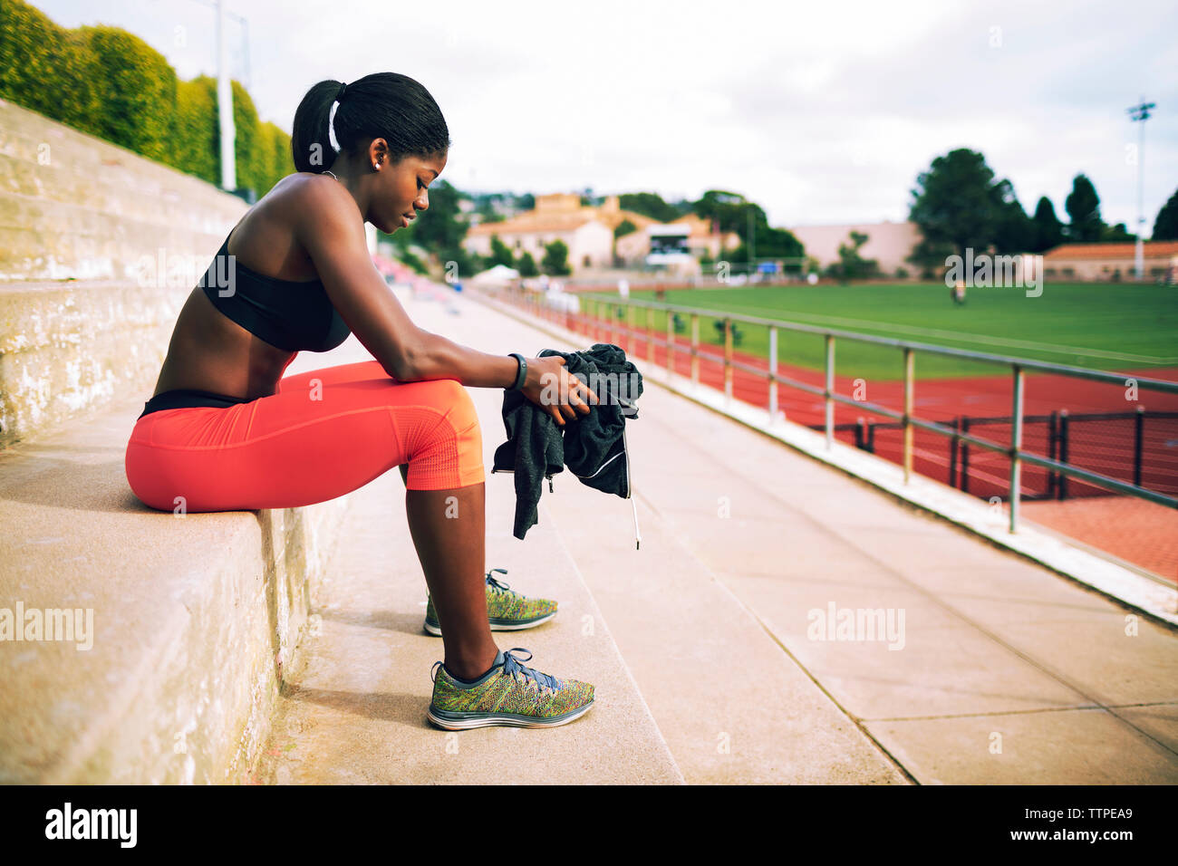 Seitenansicht der Müde weiblichen Athleten sitzen auf Schritte bei Stadion Stockfoto