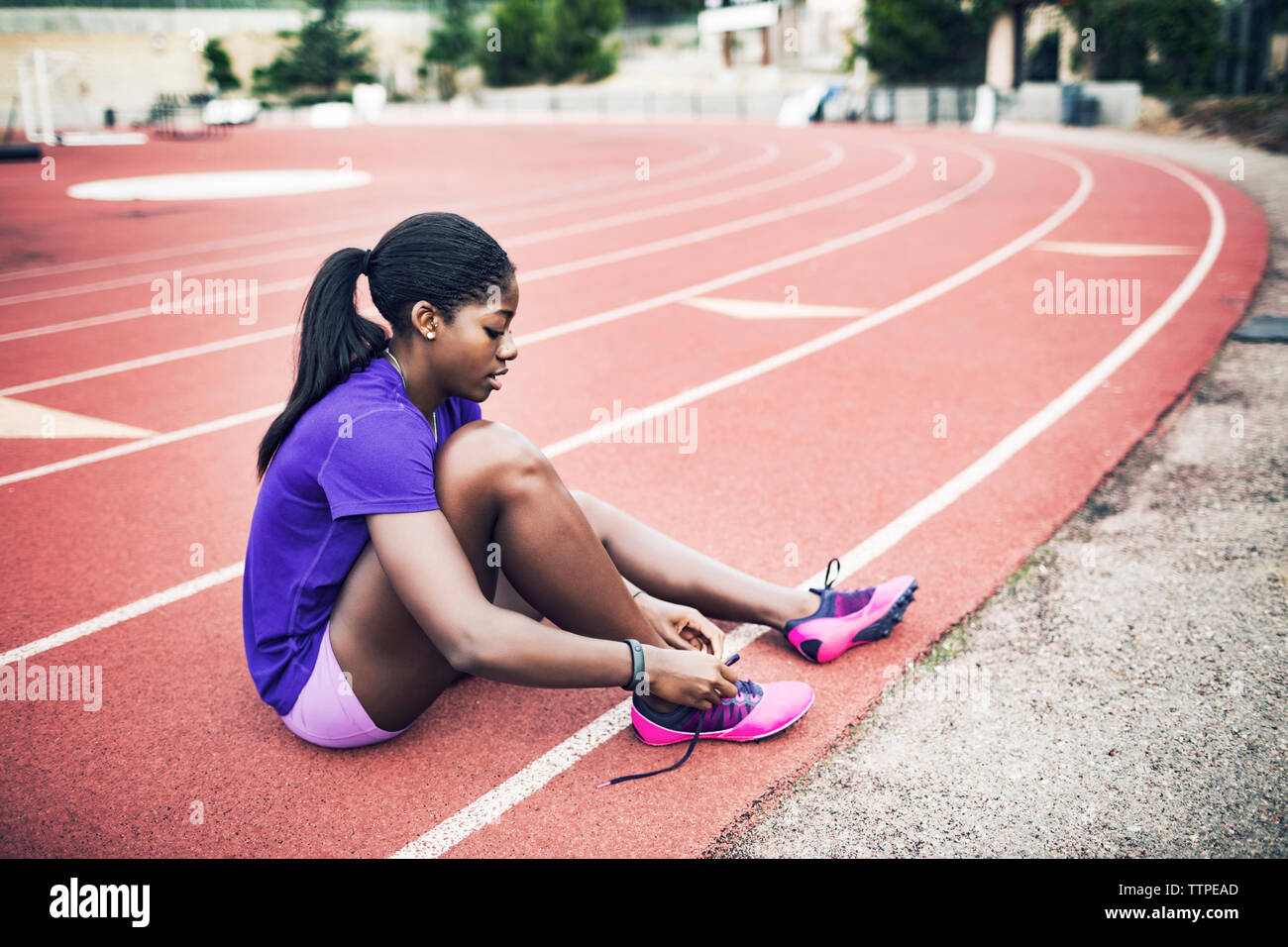Seitenansicht des weiblichen Athleten binden Schuhbändern sitzend auf Running tracks Stockfoto