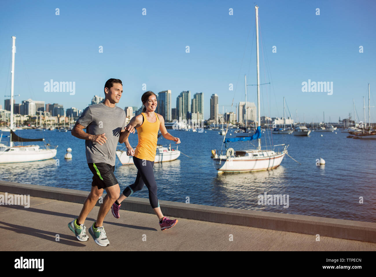 Gerne männliche und weibliche Sportler joggen am Pier von Harbour Stockfoto