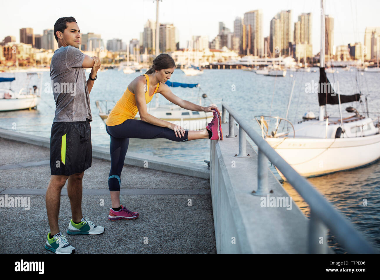 Männliche und weibliche Athleten zu tun Stretching Übungen am Pier von Harbour Stockfoto