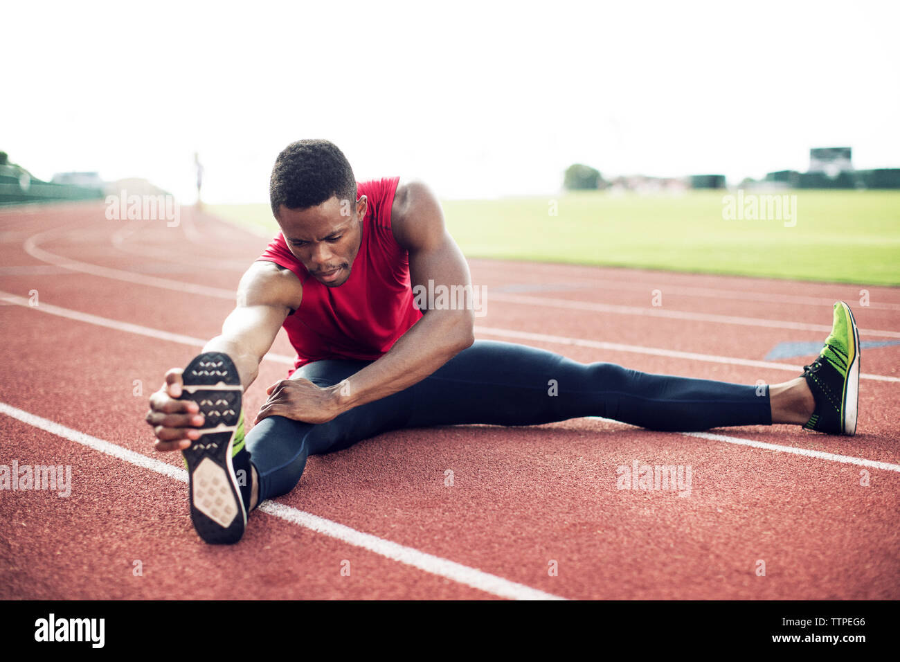Sportler Zehen berühren beim Sitzen auf Running tracks Stockfoto