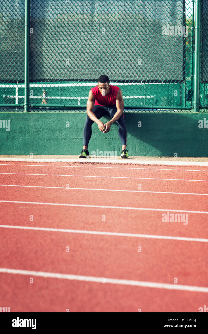 Müde Sportler sitzen auf stützmauer im Feld Stockfoto