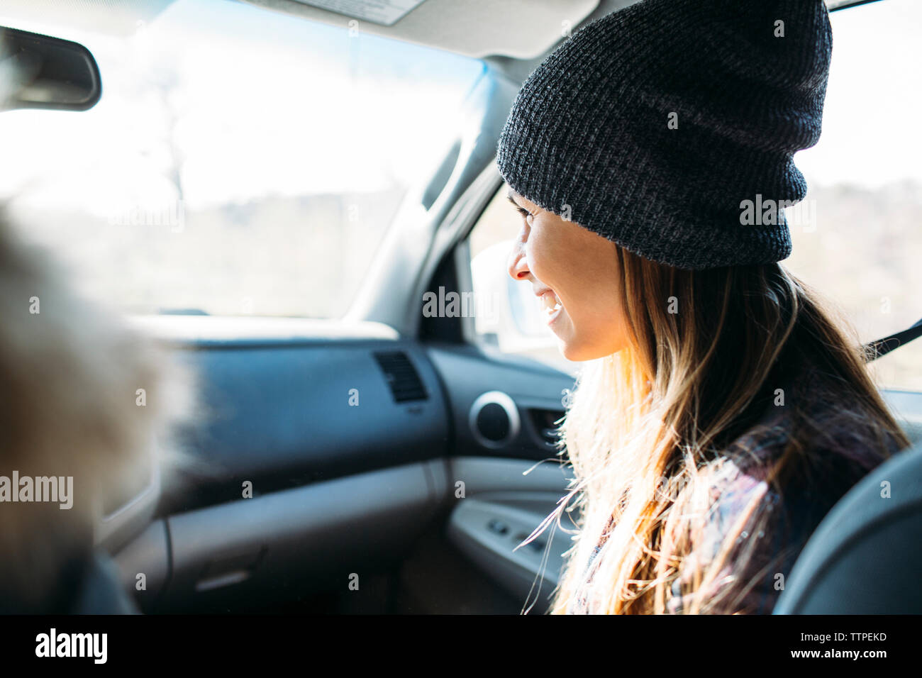 Lächelnde junge Frau im Auto während der Fahrt sitzen Stockfoto