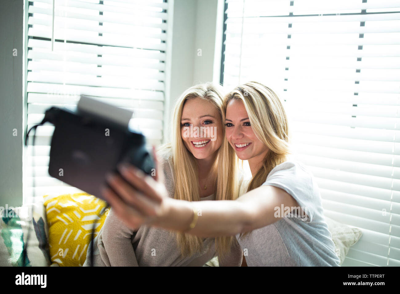 Lächelnd Freunde unter selfie während auf alkovenfenster Sitz zu Hause sitzen Stockfoto