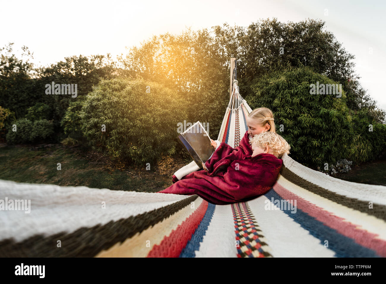 Ältere Schwester lesen zu den jüngeren Bruder in Hängematte außen Stockfoto